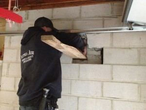 Technician performing masonry restoration on a concrete block wall, possibly part of a chimney restoration project.