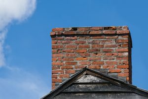 Worn brick chimney with a damaged or missing crown, indicating need for chimney crown repair or cap replacement.